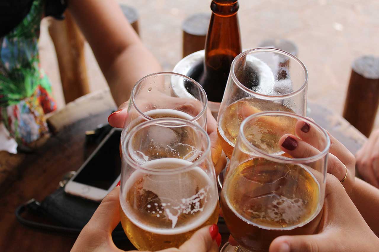 Amigos celebrando con cuatro vasos de cerveza