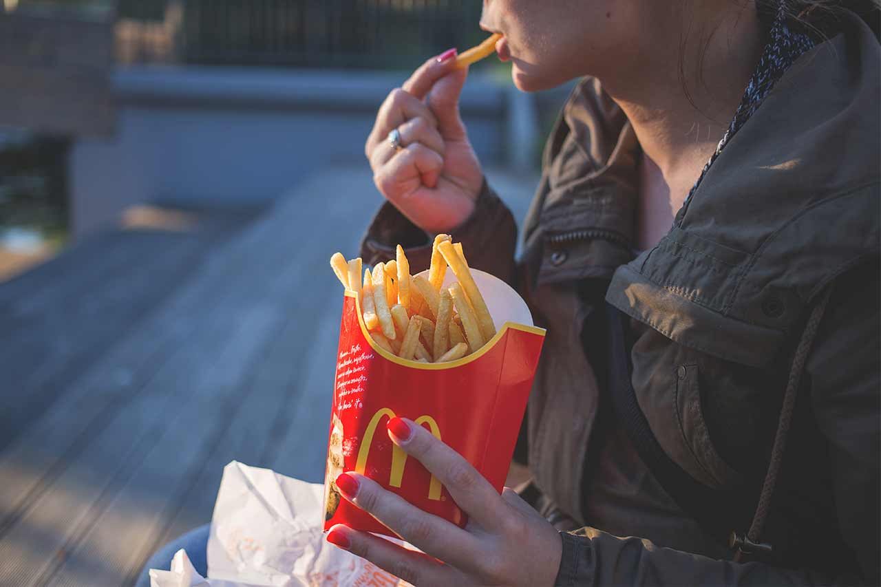 mujer comiendo papas fritas bajar de peso sin dieta