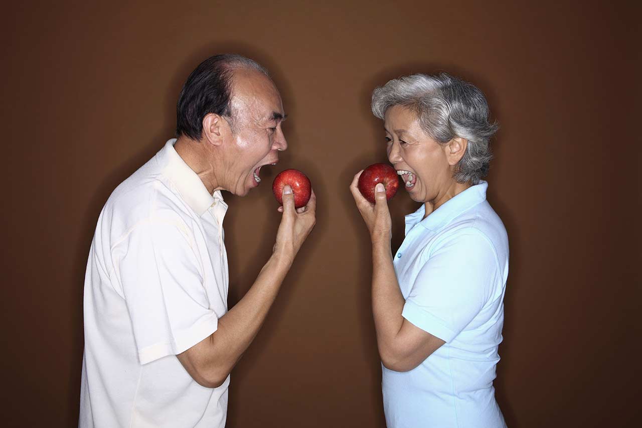 pareja de adultos mayores comiendo manzanas